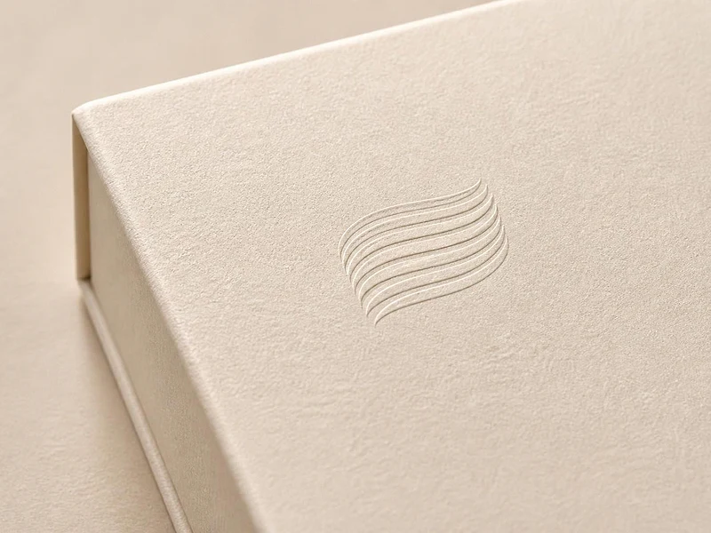 The Celiform mark blind-embossed, raised, into the cream paper of a rigid box lid